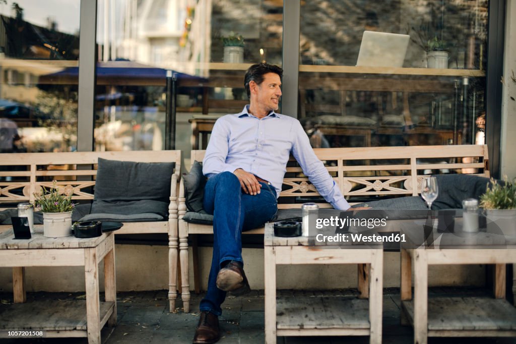 Businessman sitting in coffee shop, smiling