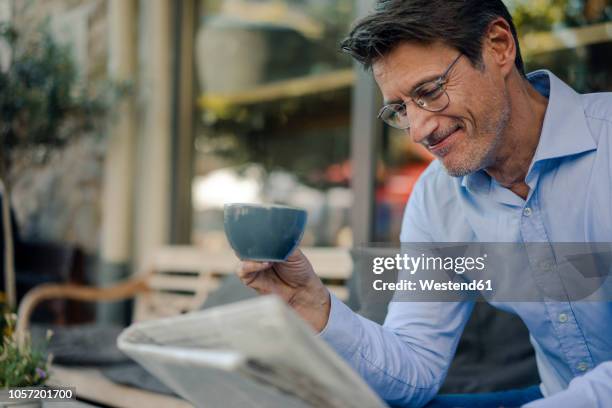 mature businessman sitting in coffee shop, drinking coffee - lesebrille stock-fotos und bilder