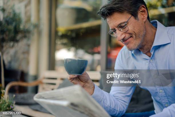 mature businessman sitting in coffee shop, drinking coffee - un solo hombre maduro fotografías e imágenes de stock
