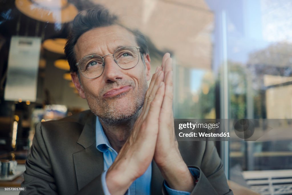 Mature businessman sitting in coffee shop, smiling