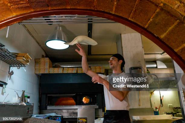 pizza baker preparing pizza in kitchen throwing dough in the air - pizza toss foto e immagini stock