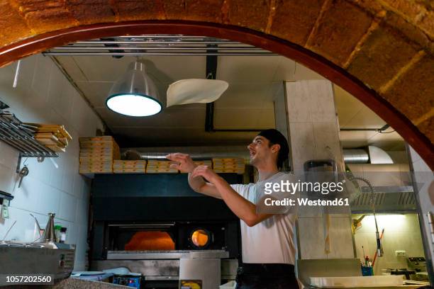 pizza baker preparing pizza in kitchen throwing dough in the air - pizza toss foto e immagini stock