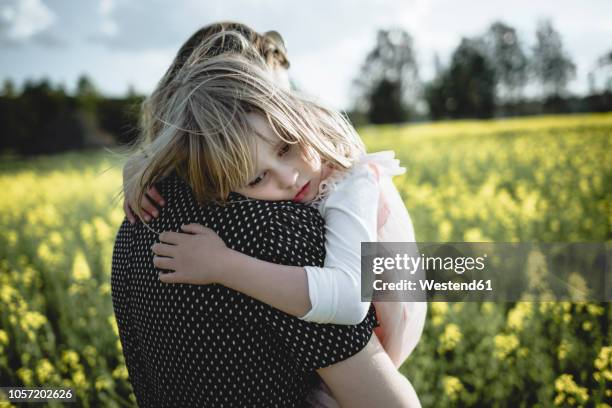 portrait of little girl on her mother's arms in rape field - head on shoulder stock pictures, royalty-free photos & images