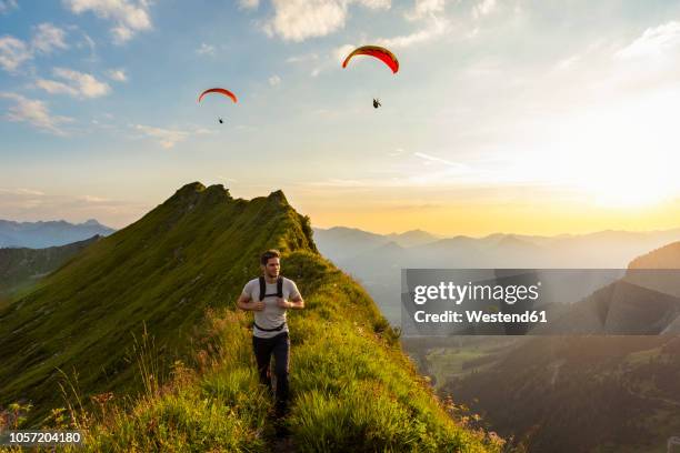 germany, bavaria, oberstdorf, man on a hike in the mountains at sunset with paraglider in background - paragliding stockfoto's en -beelden