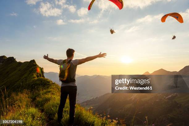 germany, bavaria, oberstdorf, man on a hike in the mountains at sunset with paraglider in background - paragliding stock pictures, royalty-free photos & images