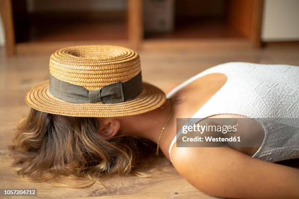 unrecognisable young woman lying on the floor with a straw hat on her head - besuch zuhause sommerlich innenaufnahme stock-fotos und bilder