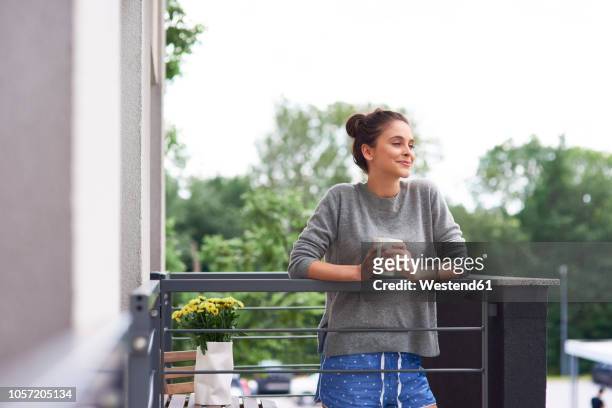 young woman drinking morning coffee on the balcony - balcony stockfoto's en -beelden