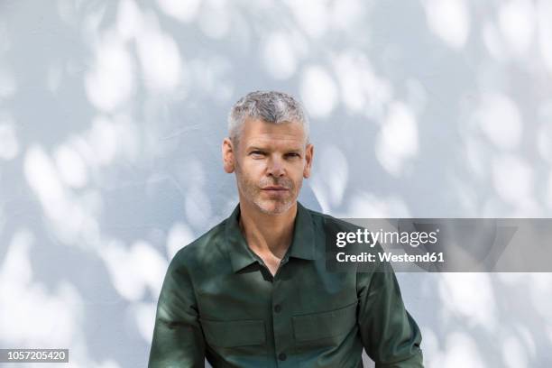 portrait of a confident mature man at white wall - grünes hemd stock-fotos und bilder