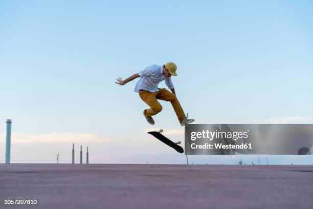 young man doing a skateboard trick on a lane at dusk - skating stock-fotos und bilder