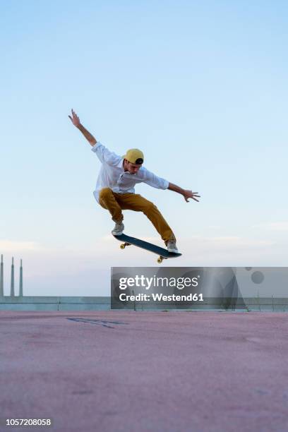 young man doing a skateboard trick on a lane at dusk - skateboardfahren stock-fotos und bilder