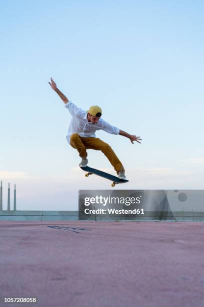 young man doing a skateboard trick on a lane at dusk - patina fotografías e imágenes de stock