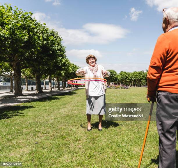 senior watching elderly lady playing with a hoola hoop - 80 89 jahre stock-fotos und bilder