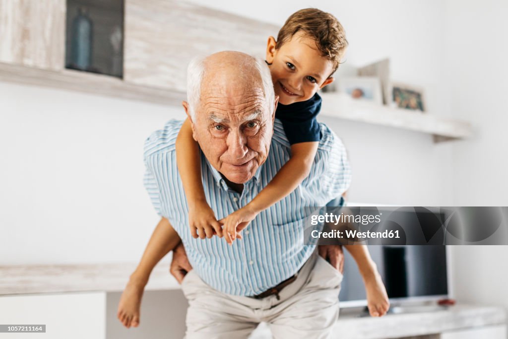 Portrait of grandfather giving his grandson a piggyback ride in the living room