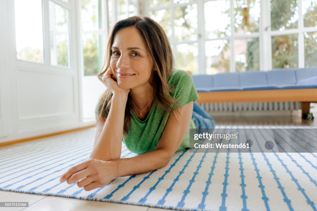 Porrait of smiling mature woman lying on the floor at home