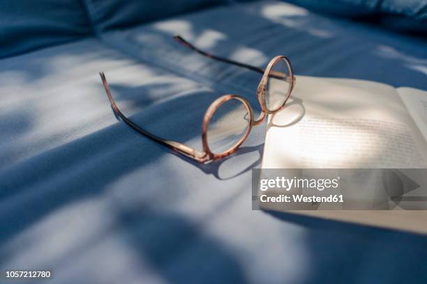 eyeglasses and book lying on couch - book blue stock-fotos und bilder