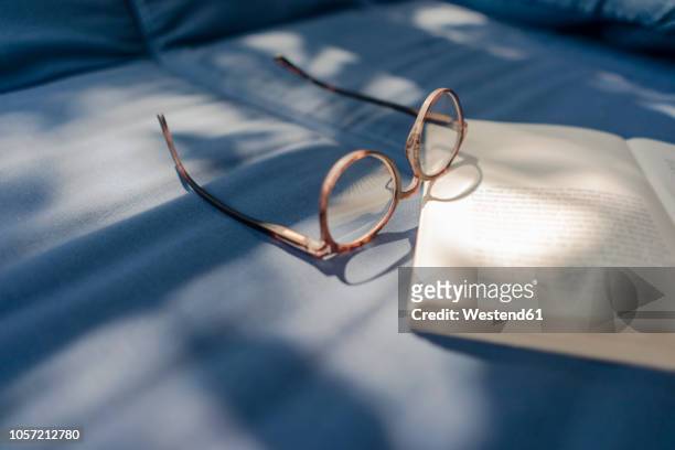 eyeglasses and book lying on couch - book blue stockfoto's en -beelden
