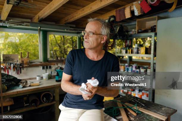 mature man in his workshop cleaning his hands - clean garage stock pictures, royalty-free photos & images