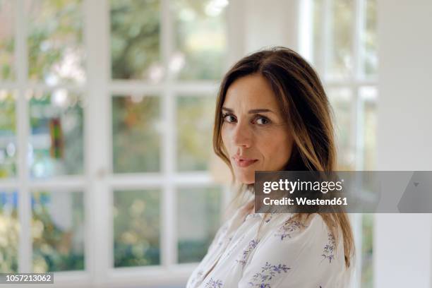 portrait of serious mature brunette woman at the window - beautiful woman 40s stock pictures, royalty-free photos & images