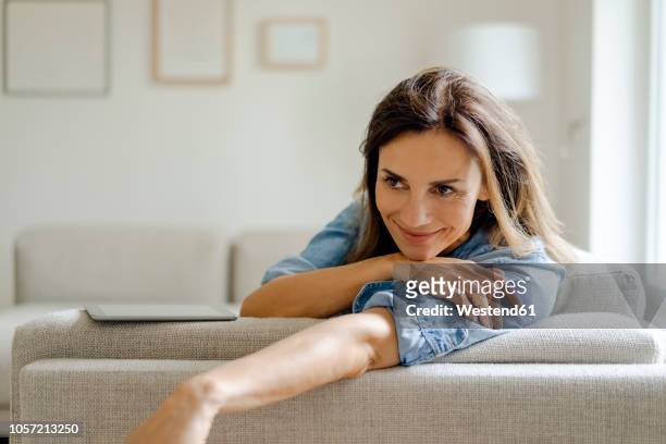 portrait of smiling mature woman resting on couch at home - quiet contemplation foto e immagini stock