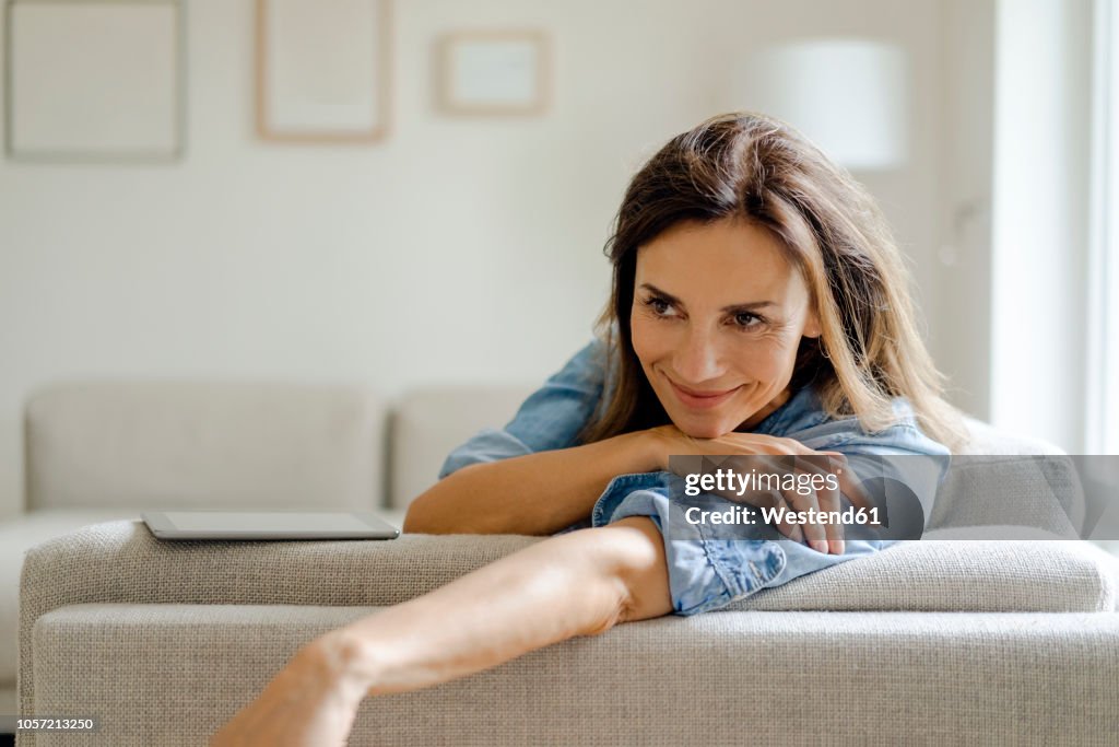 Portrait of smiling mature woman resting on couch at home