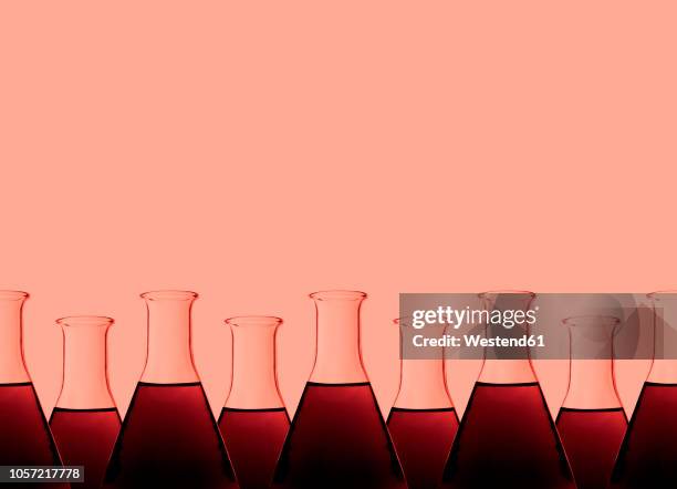 row of test tubes with liquid, red background - red tube stock-fotos und bilder