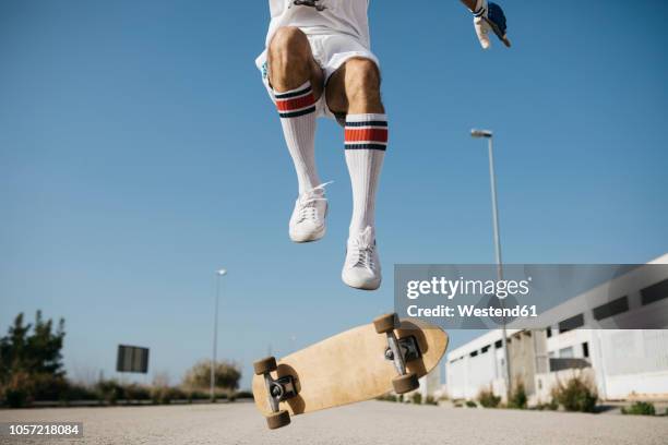 sportive man jumping above ground with skateboard performing trick - running shoes sky ストックフォトと画像