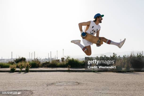 sportive man jumping above ground with skateboard on hands - hip hopper stock pictures, royalty-free photos & images
