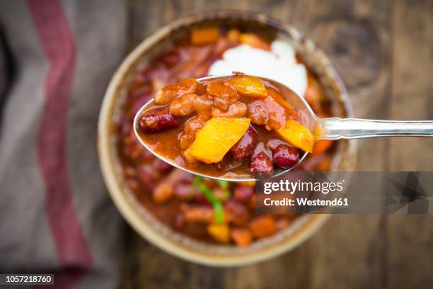 chili con carne with coriander and sour cream, spoon, close-up - chilli con carne foto e immagini stock