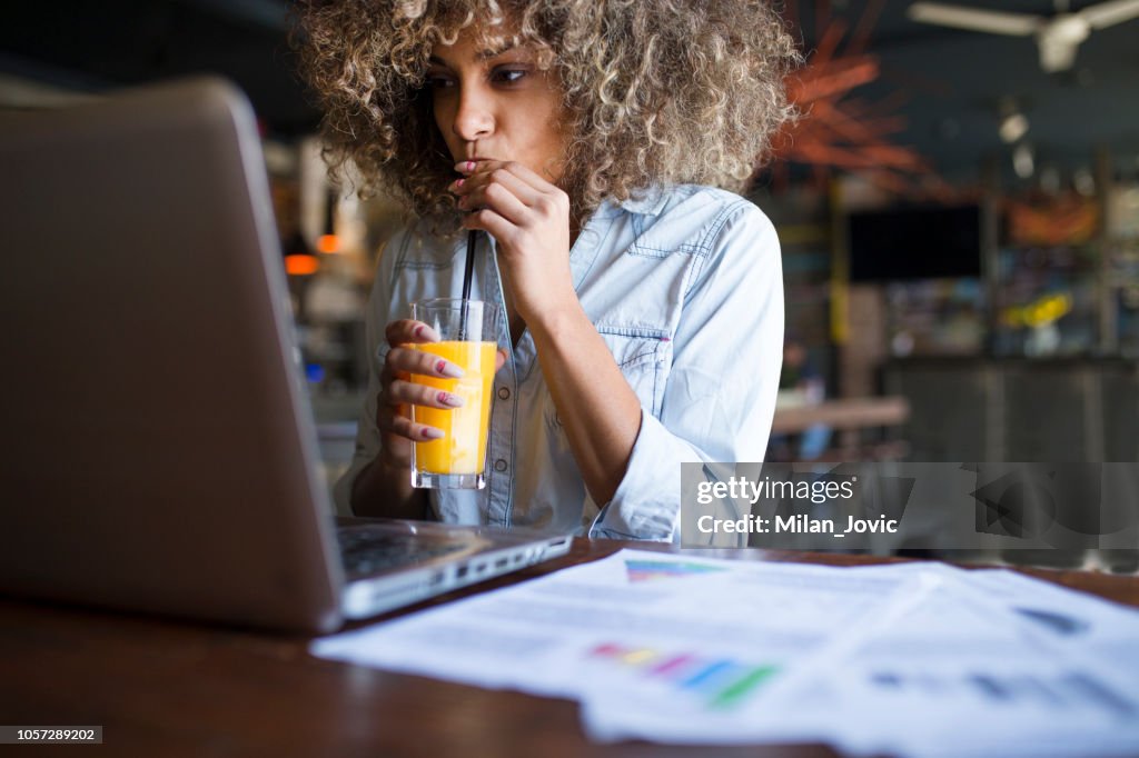 Junge afrikanische Frau online in einem Café arbeiten konzentriert