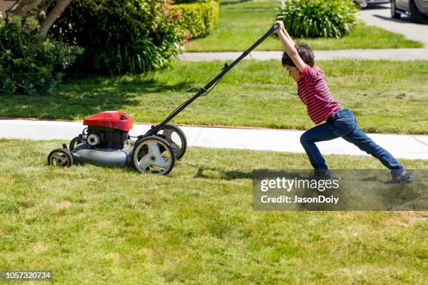 macho kid mows lawn with lawnmower - cortar relva imagens e fotografias de stock