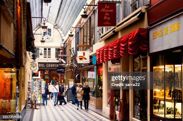 there are people, who are going shoping through passage jouffroy - shopping area with clothing stores, book stores, jewelers shops, confectionery. - storefront-for-art-and-architecture stock pictures, royalty-free photos & images