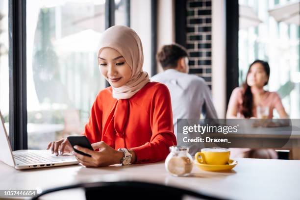 malaysian woman in cafe using electronic banking on laptop - malaysian culture stock pictures, royalty-free photos & images
