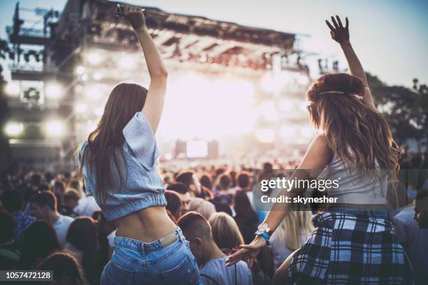 vista sul retro delle amiche che si divertono in un concerto musicale. - rock music foto e immagini stock