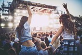 Back view of female friends having fun on a music concert.