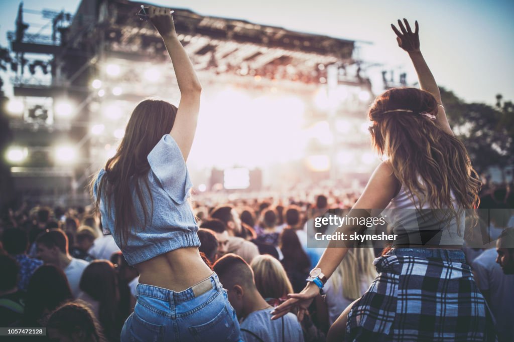 Back view of female friends having fun on a music concert.