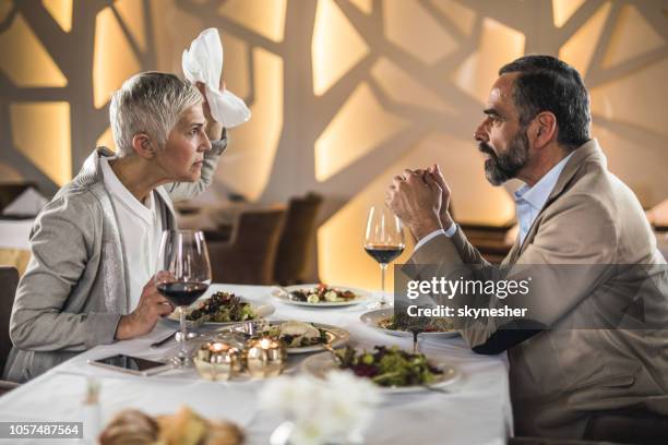 frustrated mature couple arguing on a dinner in a restaurant. - table fight stock pictures, royalty-free photos & images