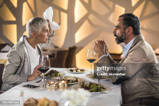 frustrated mature couple arguing on a dinner in a restaurant. - old couple restaurant stock pictures, royalty-free photos & images