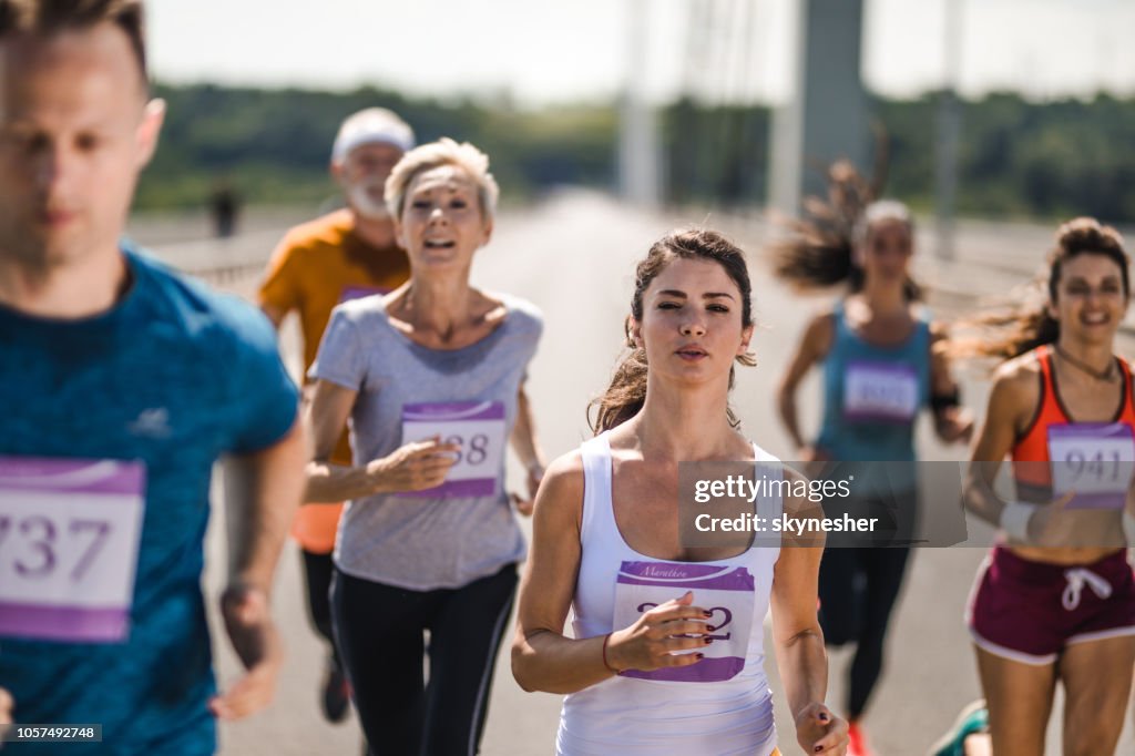 Young bepaald vrouw lopen van een marathon met andere concurrenten op de weg.
