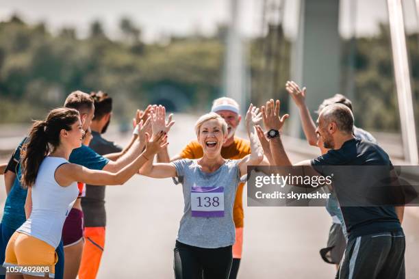 vrolijke senior loper groet haar aanhangers tijdens marathon race. - finale wedstrijd stockfoto's en -beelden