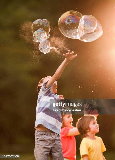 jumping to catch the rainbow bubble! - catching bubbles stock pictures, royalty-free photos & images
