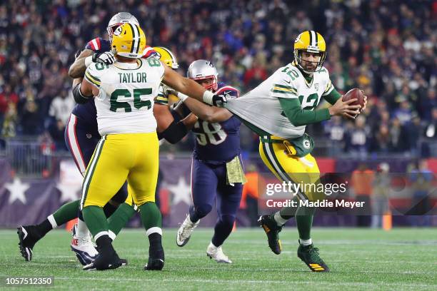 Aaron Rodgers of the Green Bay Packers looks to pass the ball as his jersey is grabbed by Lawrence Guy of the New England Patriots during the second...