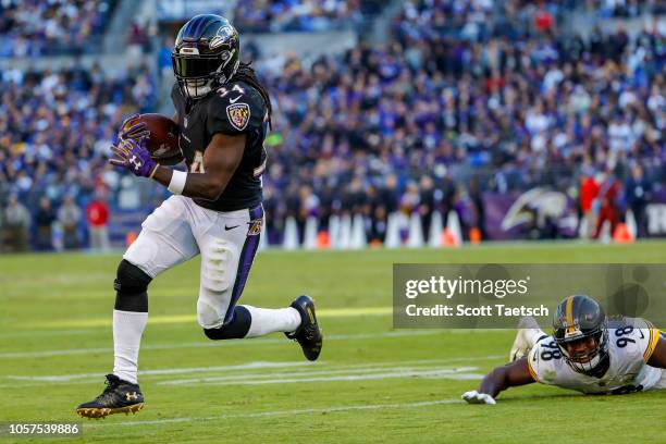 Alex Collins of the Baltimore Ravens rushes past Vince Williams of the Pittsburgh Steelers for a touchdown during the third quarter at M&T Bank...