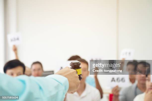 cropped hand holding gavel against people during auction - auction stock pictures, royalty-free photos & images