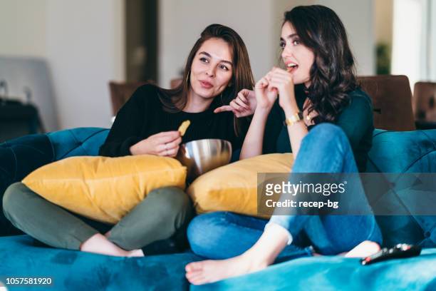 zwei junge frauen freunden vor dem fernseher zu hause - freunde couch stock-fotos und bilder