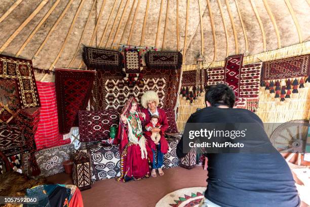 Young couple and their little baby pose in traditional Turkmen clothes in a photo studio tent near Caspian sea beach in Bondar e-Torkman, Golestan...