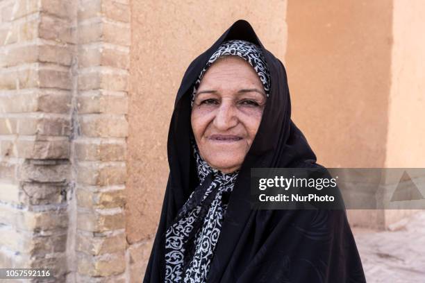 Iranian elderly woman from Balochistan region of so called Baloch people in black chador sits on a street of Yazd on September 17, 2018