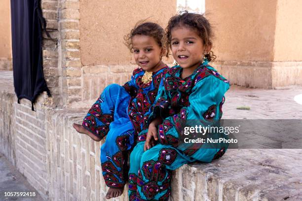 Iranian toddlers from Balochistan region of so called Baloch people in black chador sits on a street of Yazd on September 17, 2018