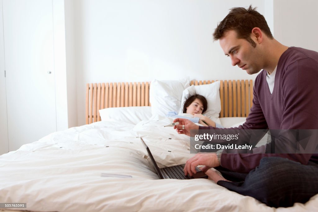 Man on laptop in bedroom