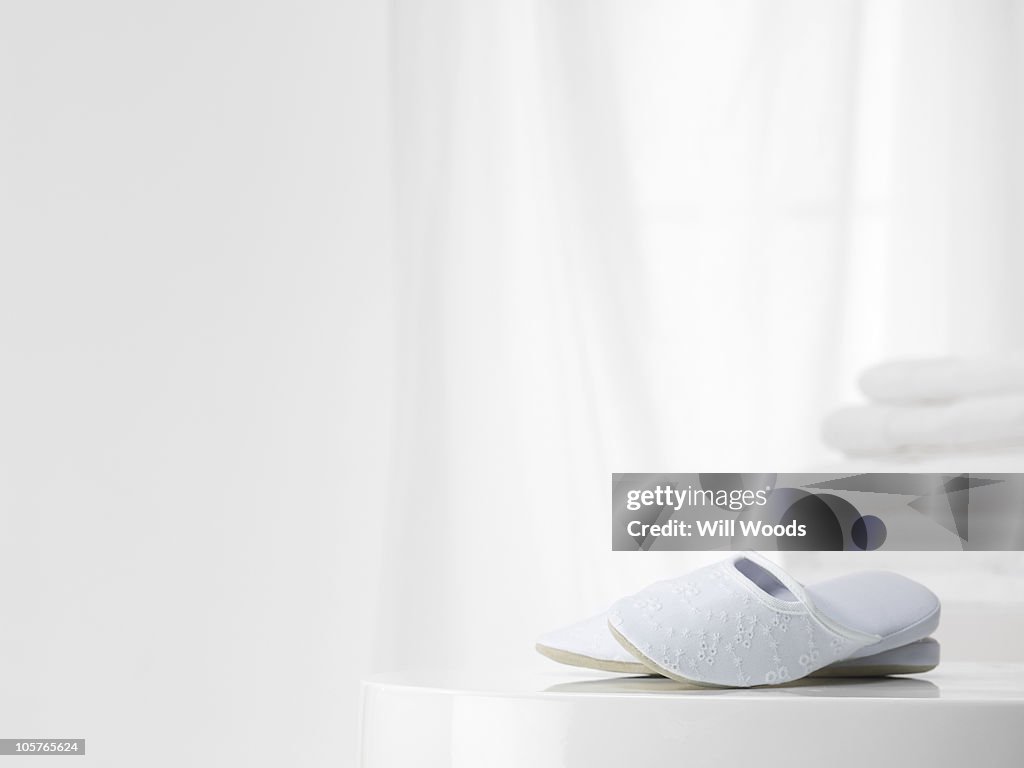 White slippers with white towles in the background