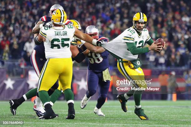 Aaron Rodgers of the Green Bay Packers looks to pass the ball as his jersey is grabbed by Lawrence Guy of the New England Patriots during the second...